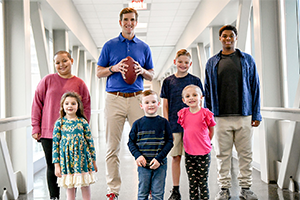 Eli standing with kids in hallway